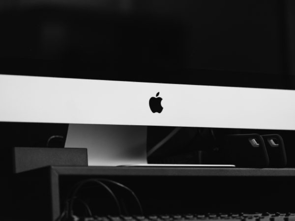 A music producer connecting a vintage iMac G3 to new Apple equipment, bridging past and present